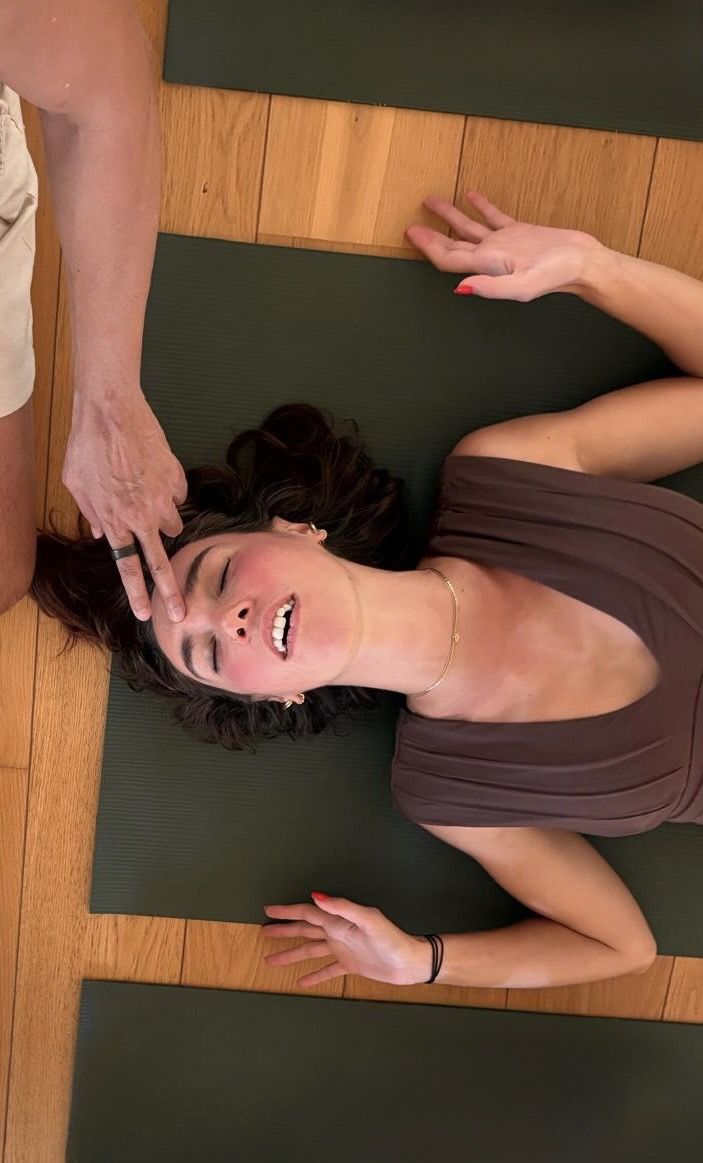 Une participante allongée, les yeux fermés, pendant que Marion pose la main sur son front